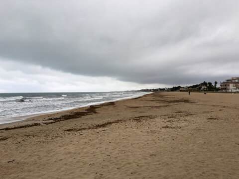 Stormy Mediterranean coastline with wide sandy beach and dramatic clouds in Oliva Spain