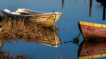 old fishing boats reflect in the harbours low water at Pin Mill Suffolk