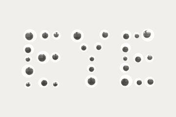 Playful arrangement of googly eyes forming the word eye on a light background.