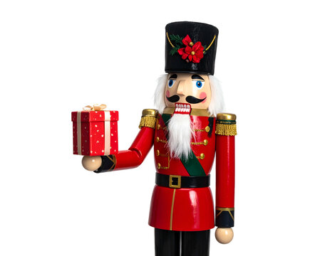 A festive wooden soldier in a red uniform, holding a wrapped gift box, on black