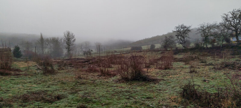 Valle monta&ntilde;oso con praderas de hierba seca y bosques caducifolios bajo un cielo gris de invierno en Palencia, Espa&ntilde;a