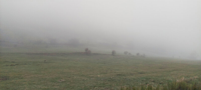 Valle monta&ntilde;oso con praderas de hierba seca y bosques caducifolios bajo un cielo gris de invierno en Palencia, Espa&ntilde;a