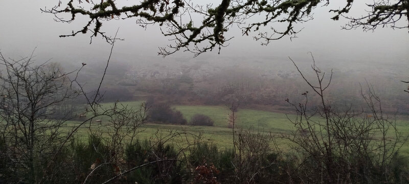 Valle monta&ntilde;oso con praderas de hierba seca y bosques caducifolios bajo un cielo gris de invierno en Palencia, Espa&ntilde;a