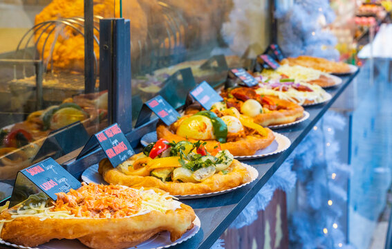 Close up of traditional Langos street food (Hungarian flatbread) with various toppings, displayed at a food stall in the Budapest Christmas Market, Hungary, December 2025