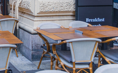 A pattern of empty tables and wicker chairs at an outdoor café terrace, decorated with simple string lights and Christmas star ornaments in Budapest, Hungary, December 2025