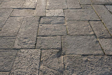 Old textured stone pavement with rectangular cobblestones lit by soft natural light