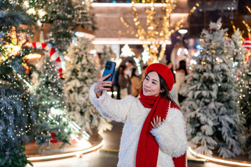 Young woman enjoying taking selfies with the romantic Christmas market decorations at night