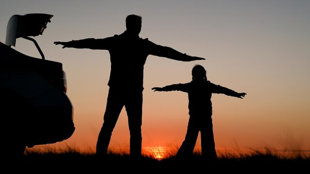 Father child daughter travel by car, admiring beautiful sky sunset. Happy family playing with hands raised, dream of flying. Father traveling by car with kid. Parent child stopped at campsite by car