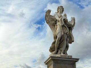 Angel with the Garment and Dice statue against heaven on the Ponte Sant'Angelo Bridge Rome Italy.
