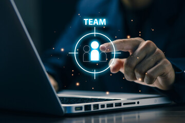 A business professional selects a team member icon on a digital interface above a laptop, representing team building, workforce targeting, leadership strategy, human resource management.