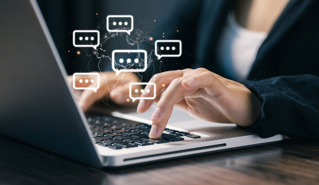 Hands typing on a laptop with floating chat bubbles over a world map, representing global online communication, instant messaging, remote collaboration, and digital business interaction.