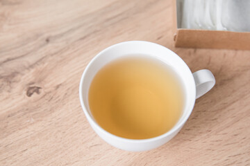 A white cup of herbal tea and a box of herbal tea