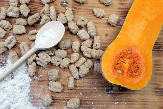 Preparation of Homemade Pumpkin Gnocchi with Flour, Wooden Spoon and Fresh Butternut Squash on Rustic Table Top View