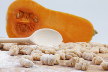 Close-up of Raw Homemade Pumpkin Gnocchi with Flour and Butternut Squash Background