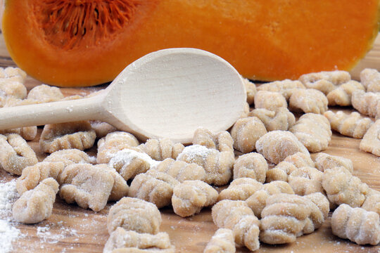 Close-up of Raw Homemade Pumpkin Gnocchi with Flour and Butternut Squash Background