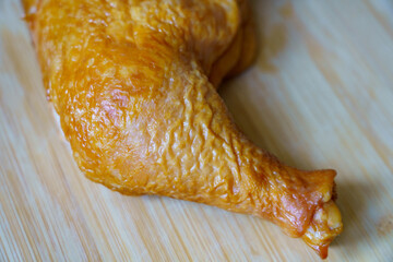 Cooked chicken leg on a wooden surface in a kitchen setting during afternoon time