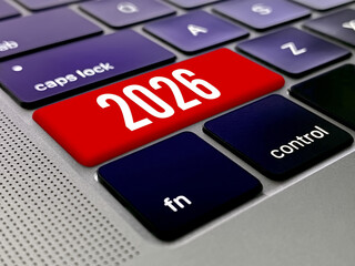 Close up macro view of a bright red keyboard key with the year 2026 printed in white, surrounded by dark blue keys on a modern laptop.