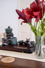 Tea ceremony arrangement. Apartment interior. Flower in transparent glass tea-board figurine ceramics cups for relaxing therapy placed on table.