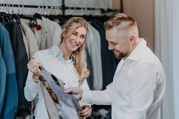 Professional fashion consultation in a modern clothing store as a customer tries on a vest and suit surrounded by elegant menswear selection