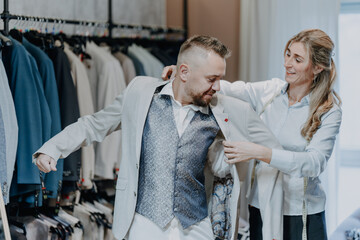 Elegant menswear boutique scene with tailor advising a customer during suit fitting focused on style quality and professional retail service