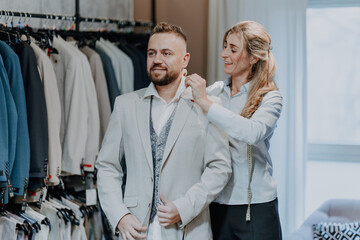 Friendly fashion expert assisting a customer with suit selection in a modern menswear boutique offering premium service and stylish clothing