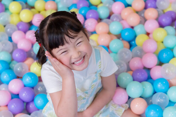 Child plays happily in colorful ball pit