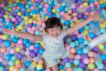 Child plays happily in colorful ball pit