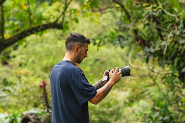 Young male photographer and hiker exploring forest trail with camera