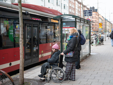 Mother and daughter waiting at a bus stop in Stockholm, Sweden, one woman using a wheelchair during a winter day