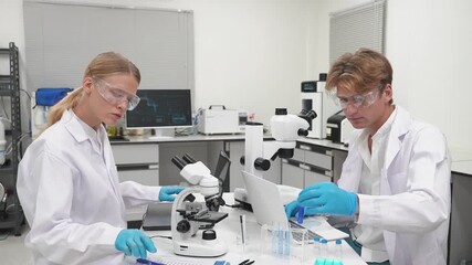 Scientists work in laboratory with microscope and test tubes during daytime research