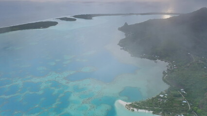 Aerial view of the stunning Bora Bora lagoon at sunrise, with a thin layer of mist hovering over...