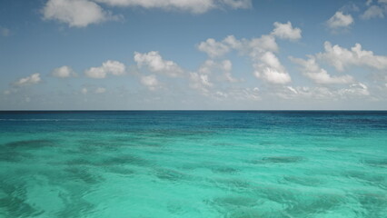 French Polynesia, Rangiroa island: stunning view of crystal clear turquoise ocean water and vast blue sky with fluffy white clouds. Breathtaking panorama of wild nature beauty. Drone flight