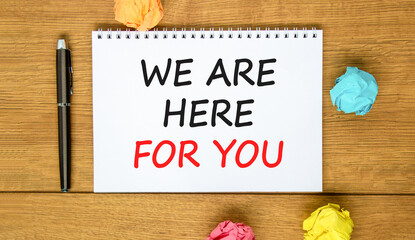 Support, help and we are here for you symbol. Concept words We are here for you on beautiful white note. Beautiful wooden background. Black pen. Business we are here for you concept. Copy space.