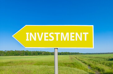 Investment symbol. Concept word Investment on beautiful yellow road sign. Beautiful blue sky green grass and forest peaceful nature background. Business investment concept. Copy space.