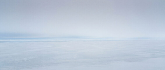 Fototapeta premium Serene winter landscape with vast white snow and soft blue sky, showcasing tranquil atmosphere. Winter scenery evokes peacefulness and calm, perfect for nature lovers and winter-themed projects.