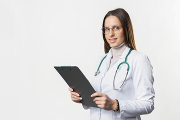 A confident-looking doctor stands against a white background holding a clipboard, smiling at the camera, showcasing her professionalism and approachability 