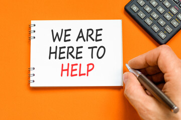 Support, help and we are here to help symbol. Concept words We are here to help on beautiful note. Beautiful orange background. Businessman's hand. Business we are here to help concept. Copy space.