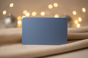 Obraz premium Blank blue card on a beige fabric with christmas lights