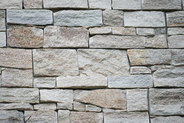 Natural granite stone wall with rougly surface, alignment in horizontal layer. Building exterior bacground or texture.