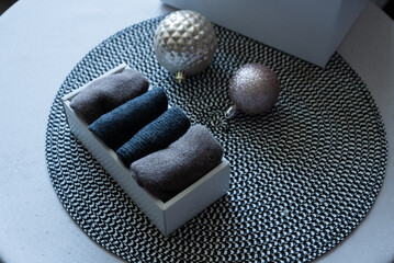 Folded knit textiles in box with Christmas ornaments on table