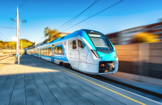 High-speed blue passenger train moving at railway station platform at sunset. Train station. Modern railway transportation concept with motion blur effect. Railroad. Commercial transport in Slovenia