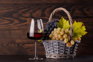 Obraz premium Red wine glass and basket of fresh grapes