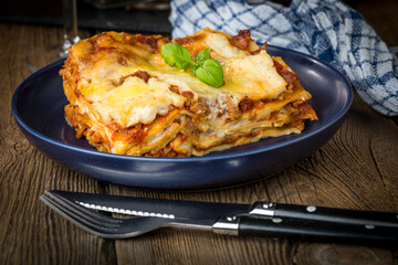 Piece of tasty hot lasagna with red wine.