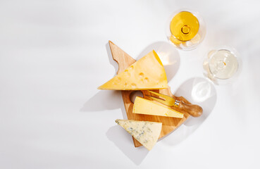 Obraz premium Assorted cheeses and wine glasses on white background