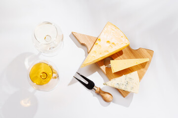 Obraz premium Assorted cheeses and wine glasses on white background