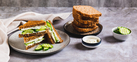 Cucumber sandwich with butter and cream cheese on a plate on the table web banner
