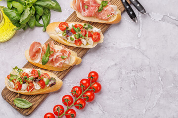 Tasty antipasto toasts featuring classic caprese with mozzarella and tomatoes, and savory prosciutto with herbs
