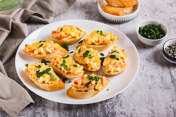 Baked sandwiches with crab salad and greens on a plate on the table