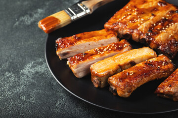 Hot grilled spare ribs from a summer BBQ served on a plate with sauce. Top view. Copy space