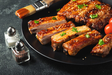 Hot grilled spare ribs from a summer BBQ served on a plate with sauce. Top view. Copy space